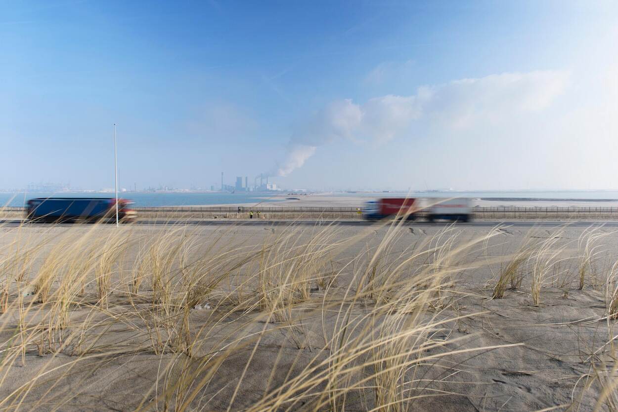 Een weg met auto's en fabriek op de achtergrond