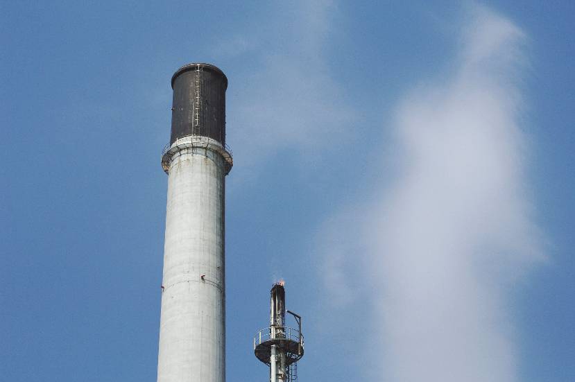 Schoorsteen van een raffinaderij tegen een blauwe lucht