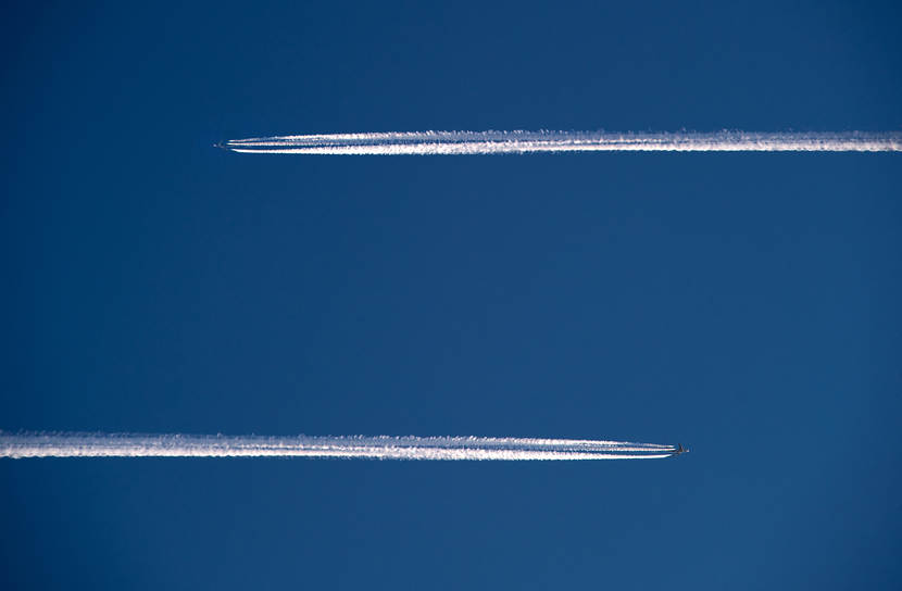Twee vliegtuigen hoog in de lucht die in tegengestelde richting vliegen